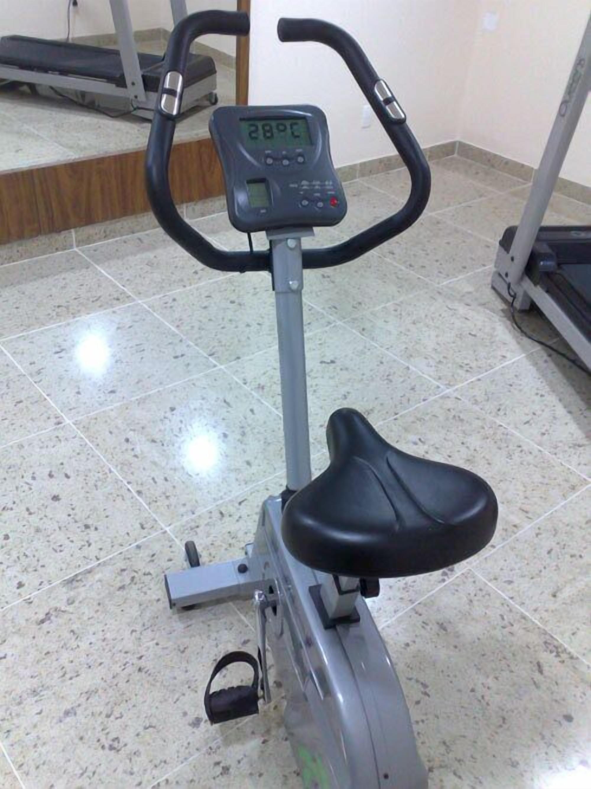 Un vélo d’appartement doté d’un écran numérique, d’une selle et de pédales.