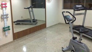 A gym with a treadmill, an elliptical, and a weight rack. - Hotel Pedra Negra (Governador Valadares)