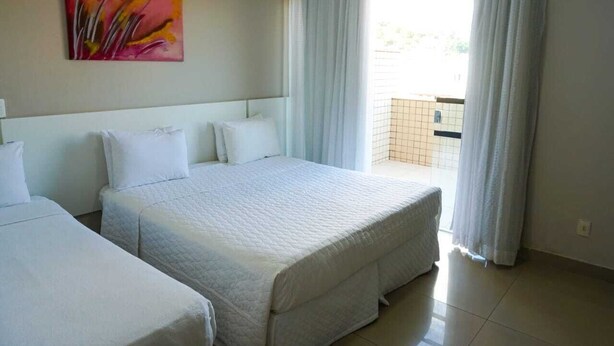 A hotel room with a large bed, a smaller bed, and a painting on the wall. - Hotel Pedra Negra (Governador Valadares)