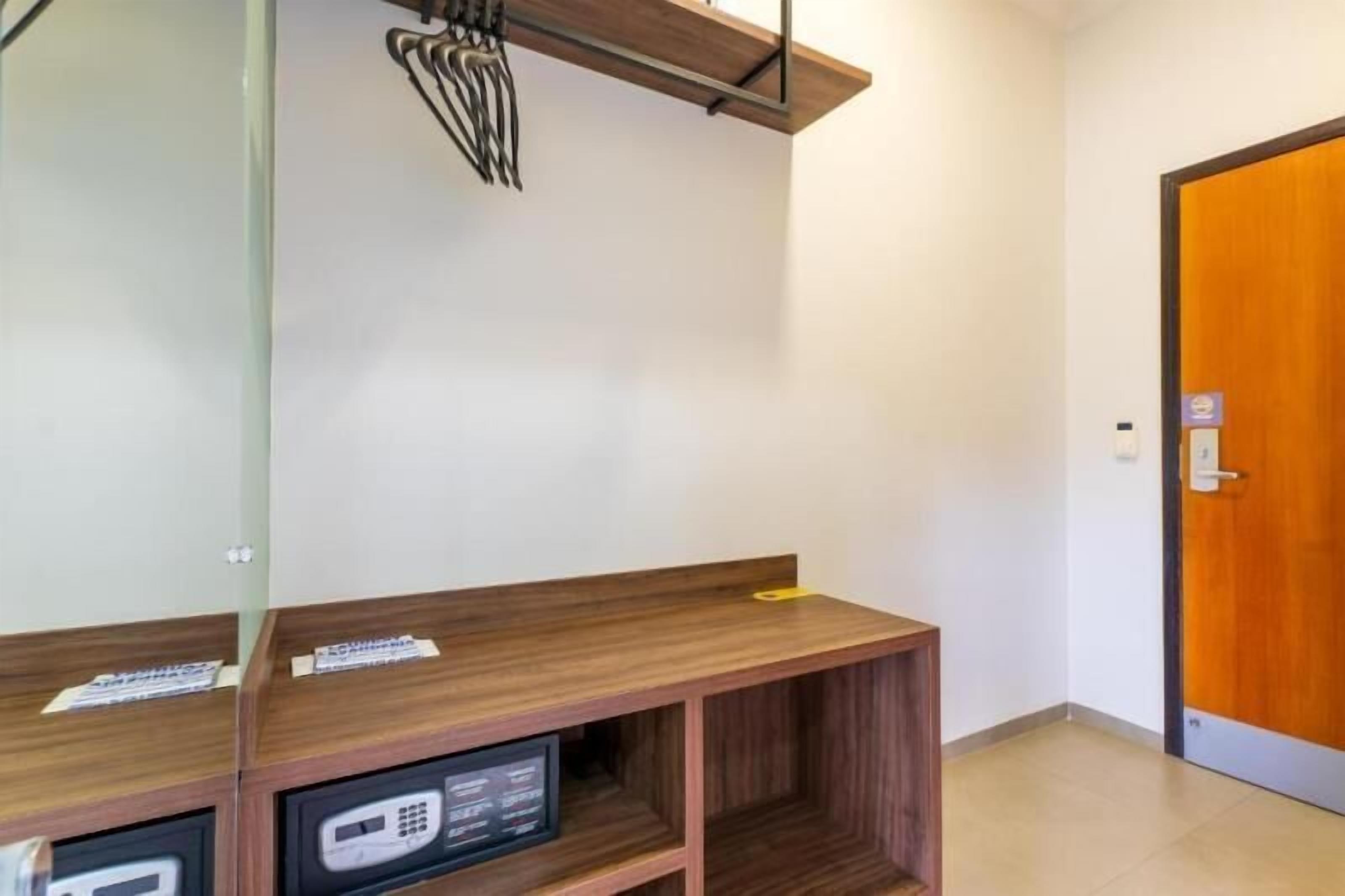 A hotel room with a wooden desk, a mirror, and a door.