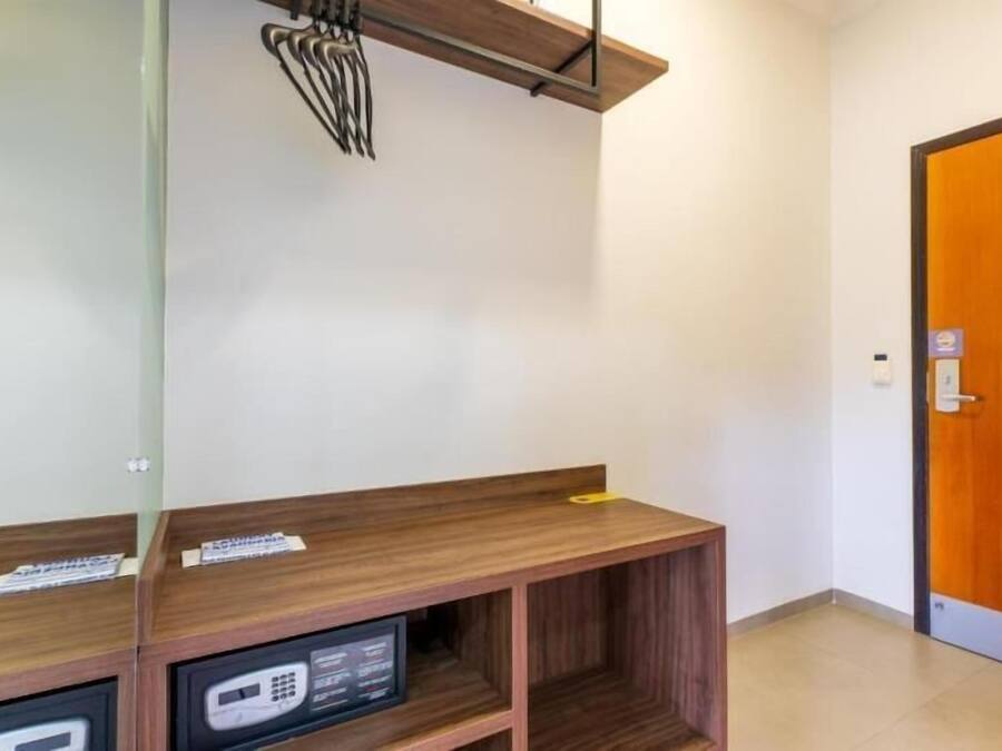 A hotel room with a wooden desk, a mirror, and a door.