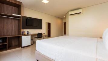 Una habitación de hotel moderna con una cama grande, un escritorio, un armario y un televisor de pantalla plana.