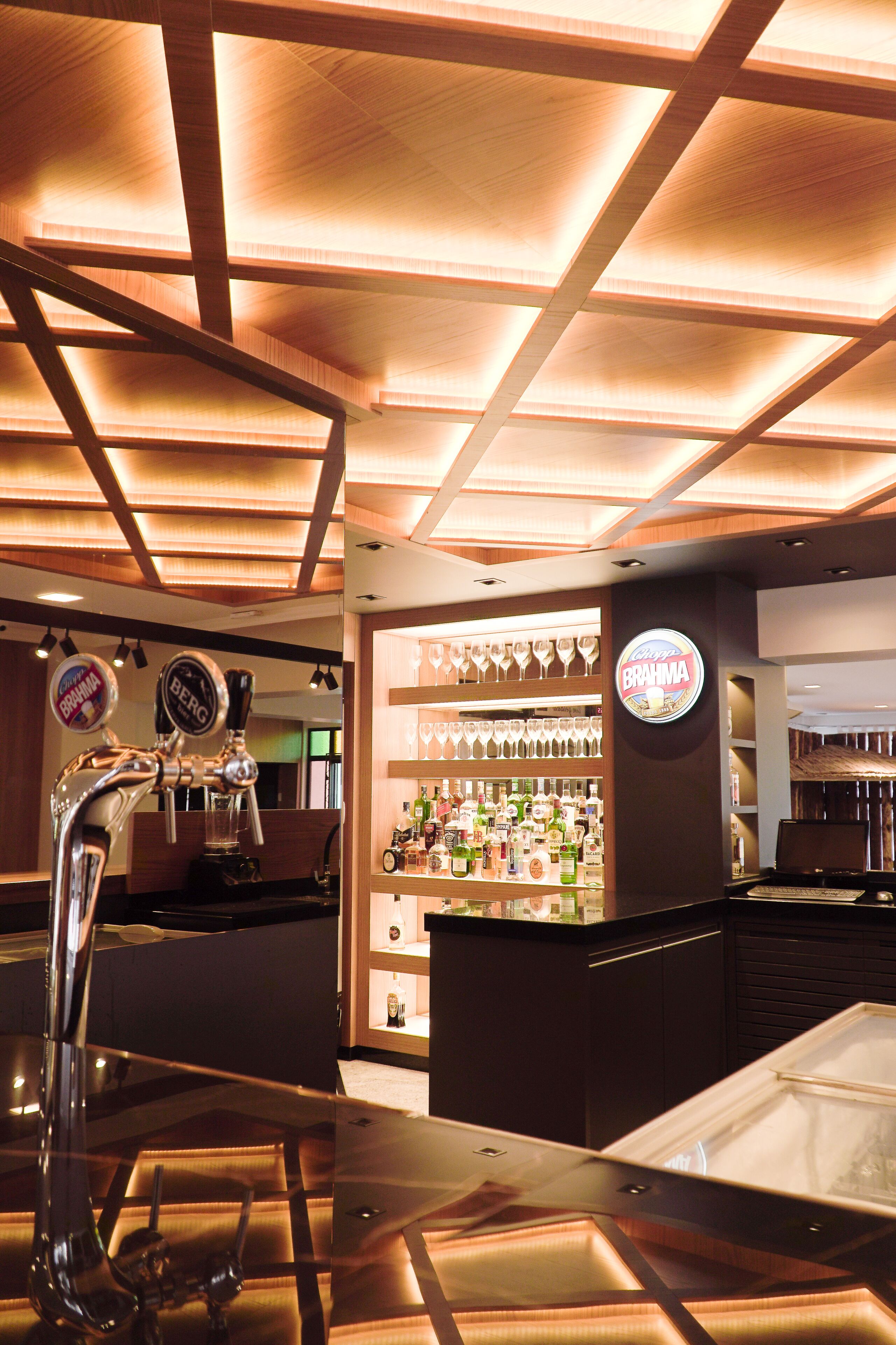 A bar area with a tap, shelves with bottles, and a sign that reads "Brahma".