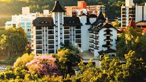 Ein Hotel mit einem zentralen Turm, mehreren Balkonen und einer üppigen, grünen Umgebung.