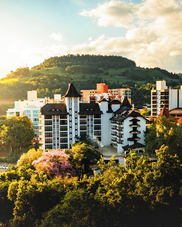 Ein Hotel mit einem zentralen Turm, mehreren Balkonen und einer üppigen, grünen Umgebung.