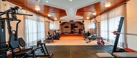 Un gimnasio con varios equipos de ejercicio, una cinta de correr y una banca.