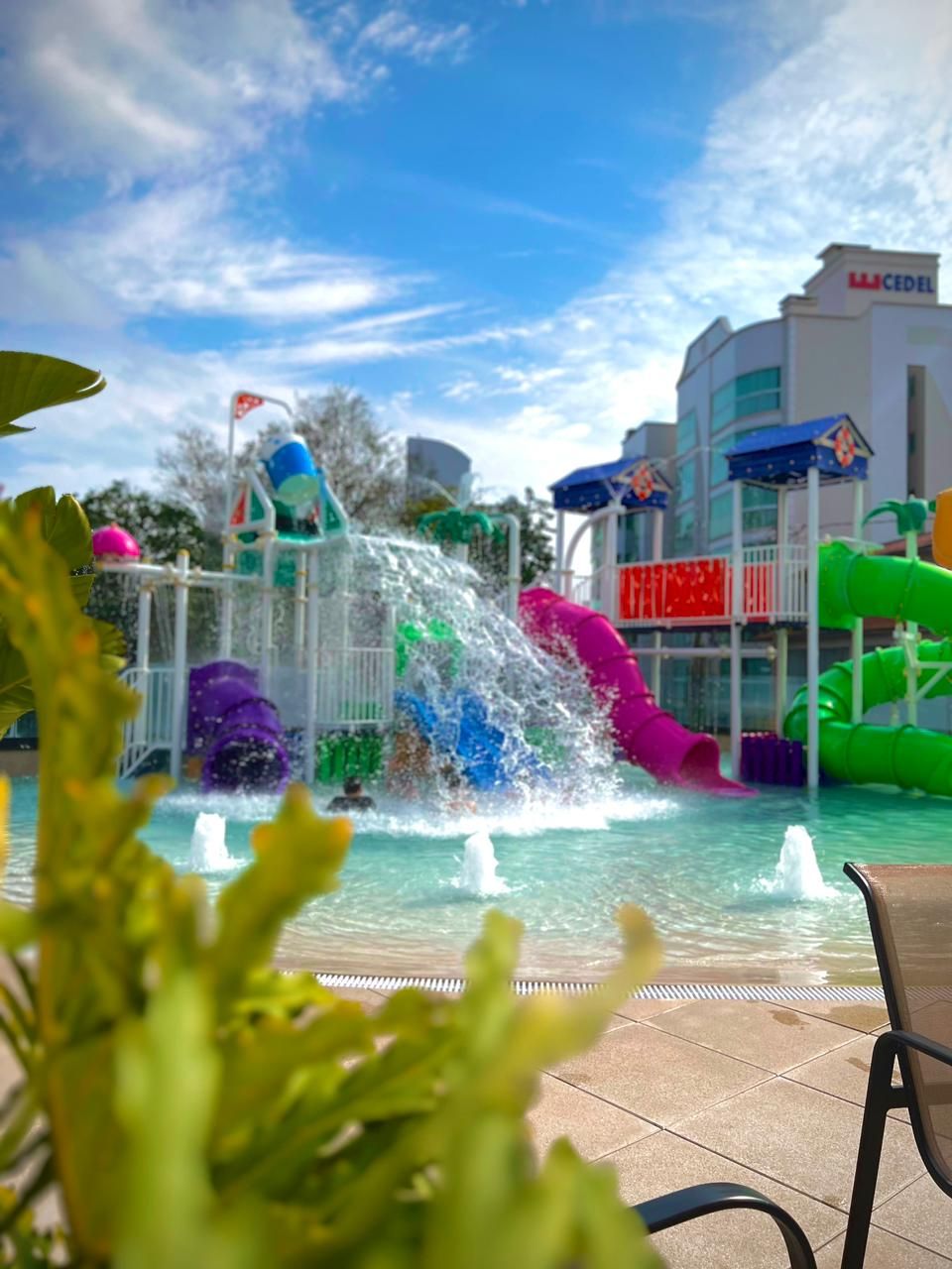 Un parc aquatique doté de nombreux toboggans et d’autres attractions aquatiques, d’une piscine et d’un bâtiment avec des panneaux indicateurs.