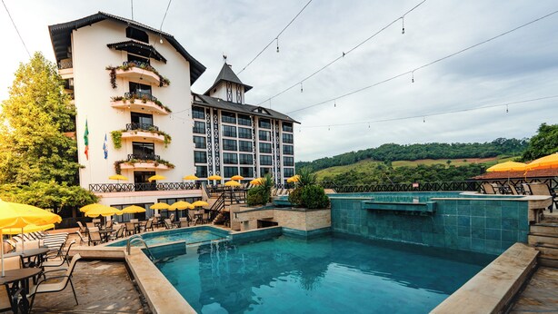 Ein Hotel mit Schwimmbad, Sitzgelegenheiten im Freien und Blick auf die umliegende Landschaft.