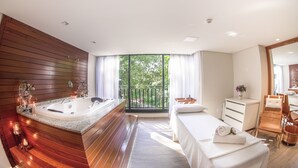 Ein modernes Badezimmer mit einer großzügigen Badewanne, einem Holzbadezimmer-Möbel und einem Balkon mit Blick auf Bäume.