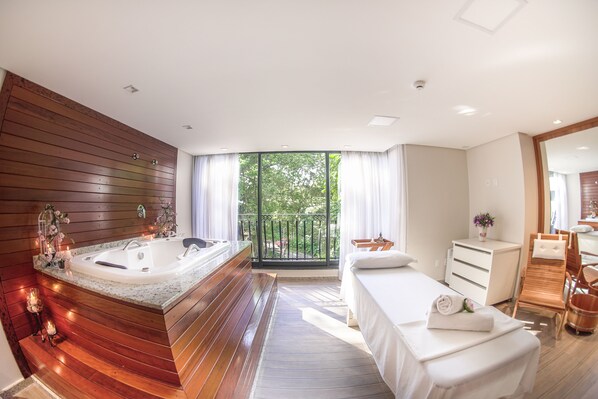 Une salle de bain moderne avec une grande baignoire, un meuble-lavabo en bois et un balcon offrant une vue sur les arbres.