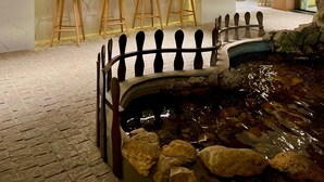 Zona de bar con taburetes, una barra con botellas y una pequeña fuente interior.