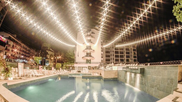 Zona de piscina con una fuente central, rodeada de sillones de descanso y una zona de bar.