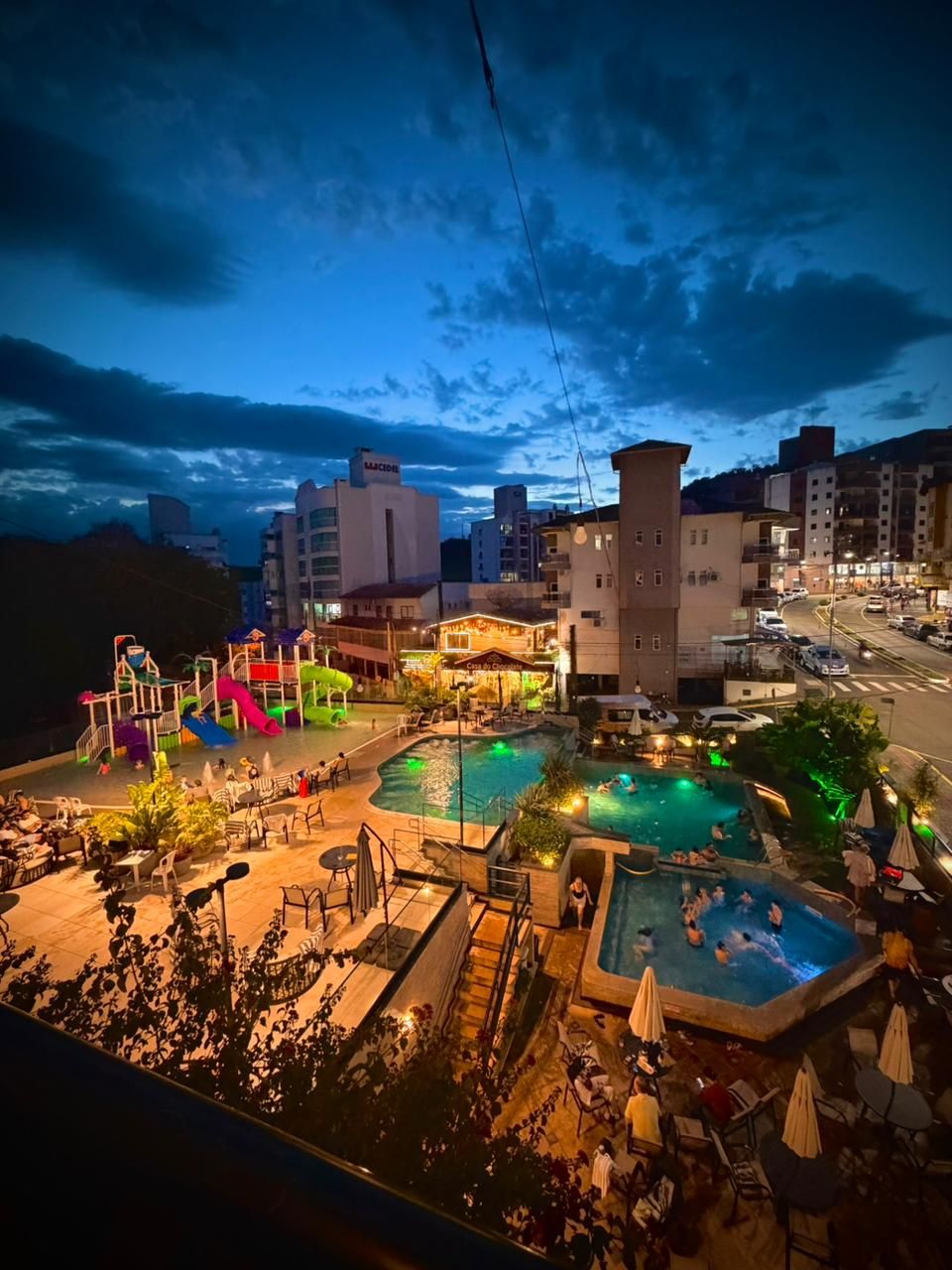 Un hotel con múltiples piscinas, una zona de juegos para niños y un restaurante.
