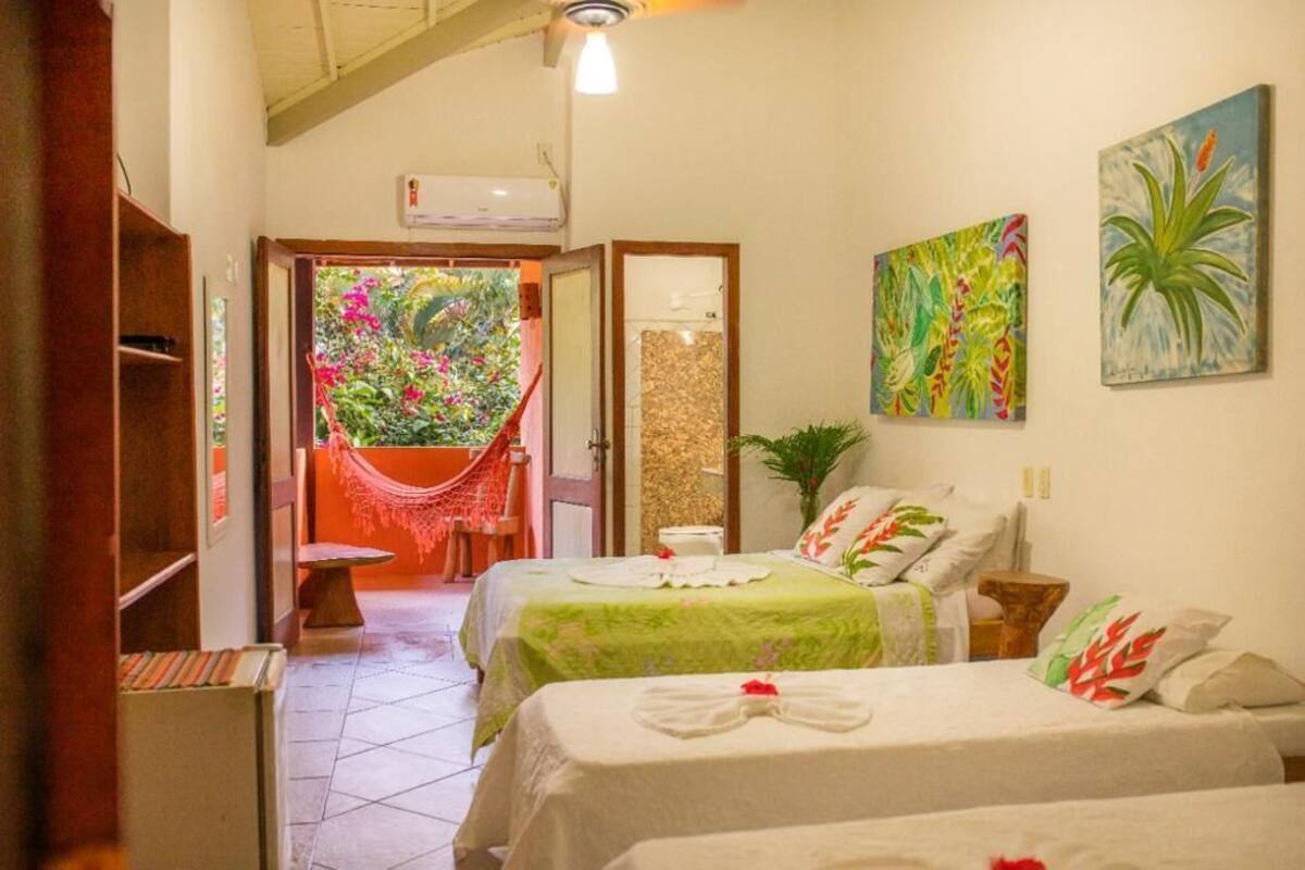 Quarto de hotel com duas camas, uma rede e vista para um jardim.