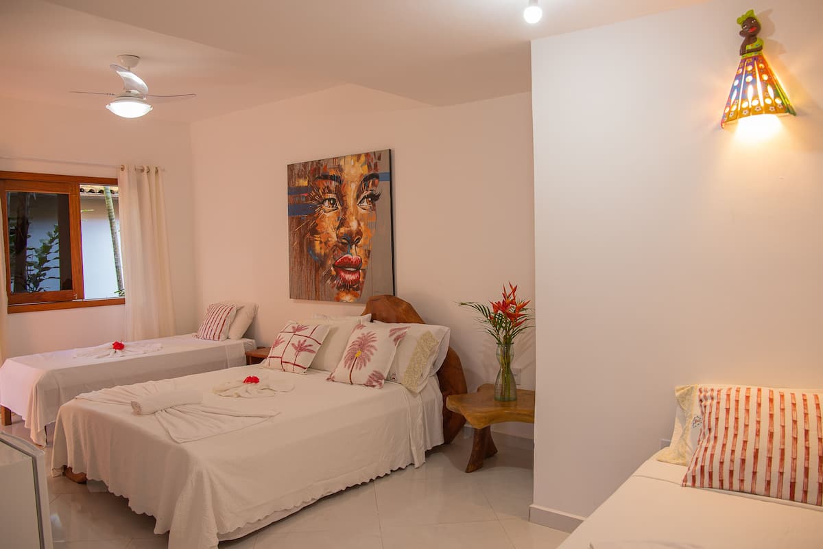 Quarto de hotel com duas camas, um ventilador de teto, um quadro na parede e uma luz noturna.