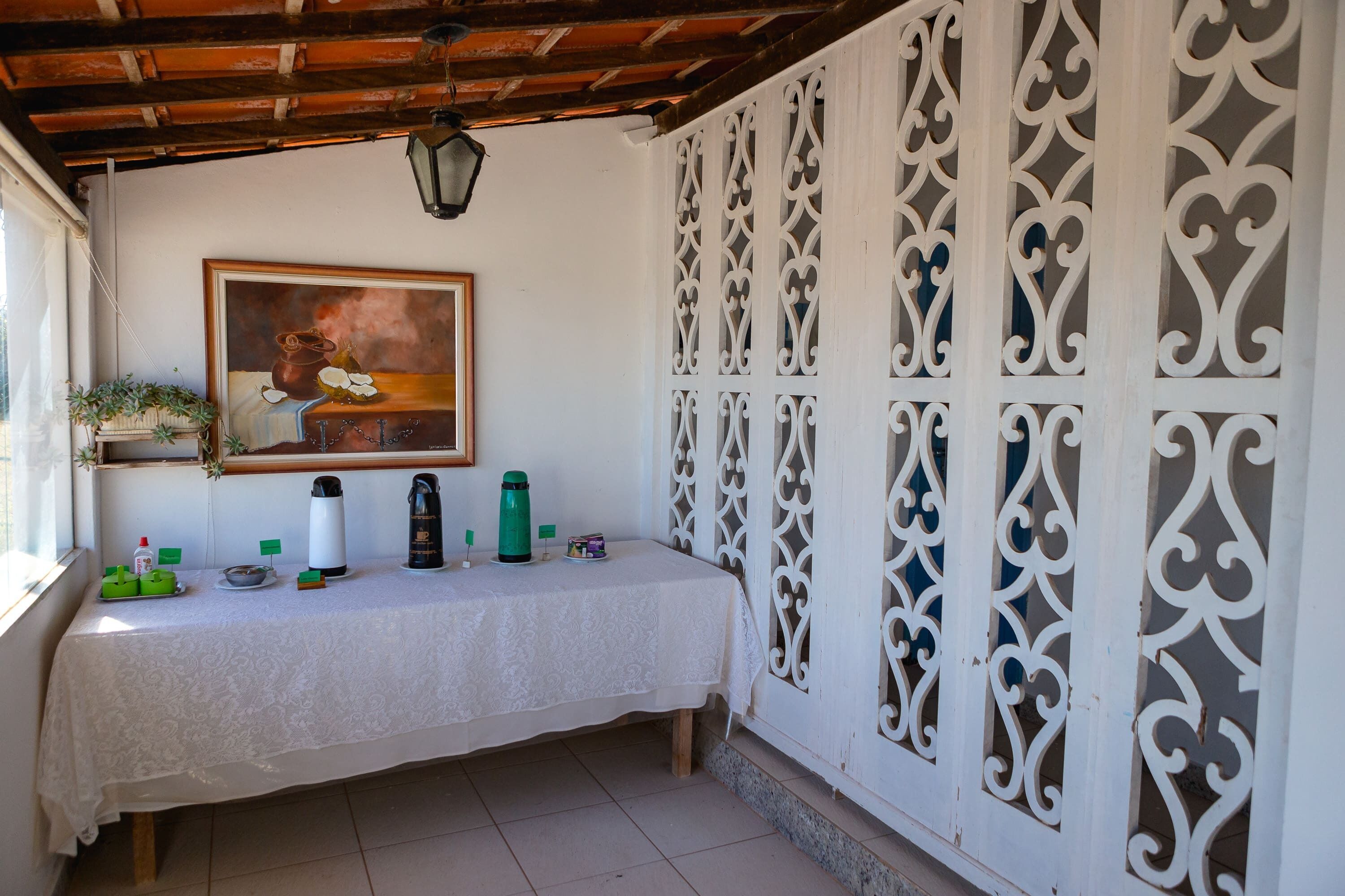 Una habitación con una mesa cubierta por un mantel blanco, un cuadro en la pared y un separador blanco decorativo con diseños intrincados.
