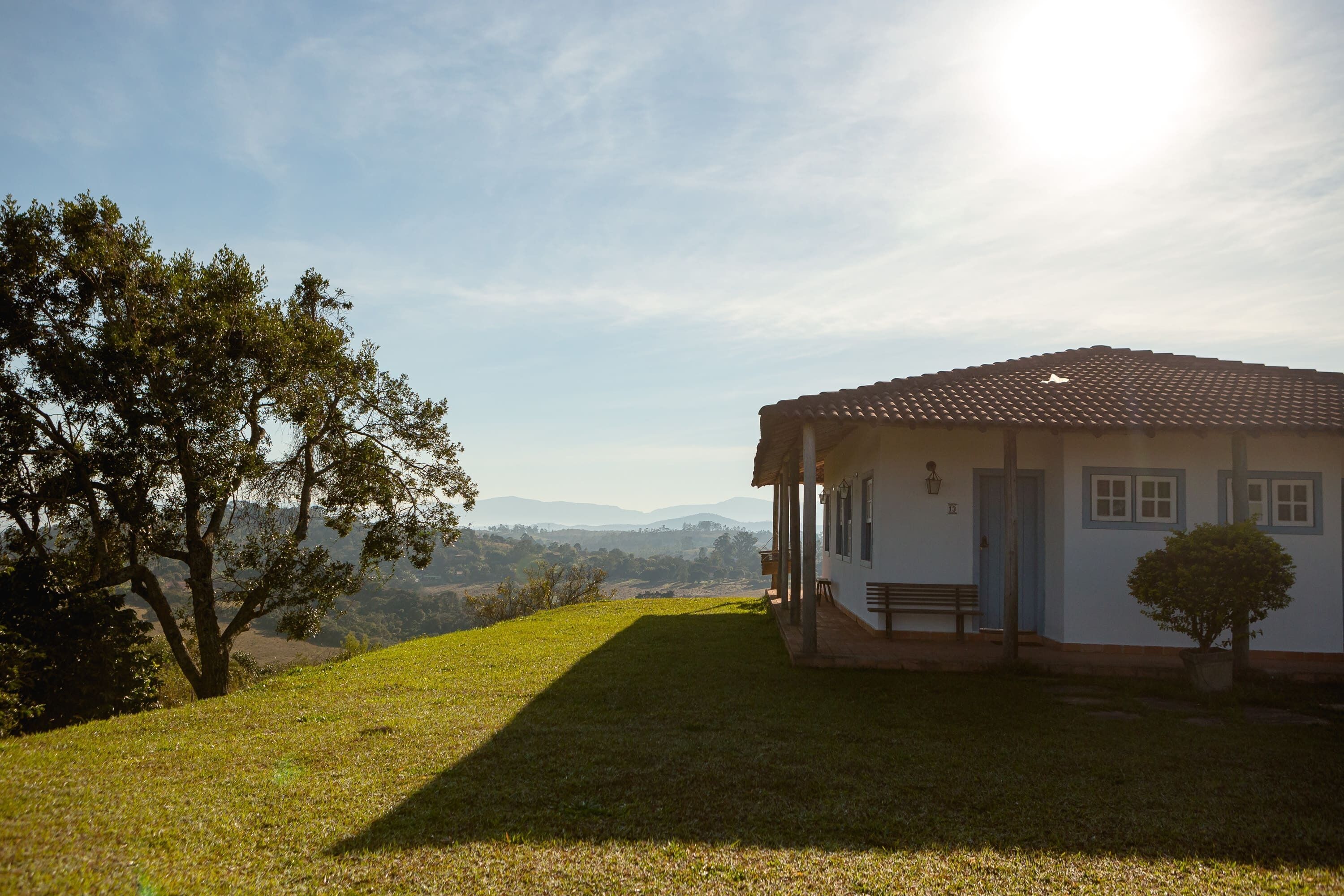 A house with a tiled roof, a porch, and a small tree in front.
