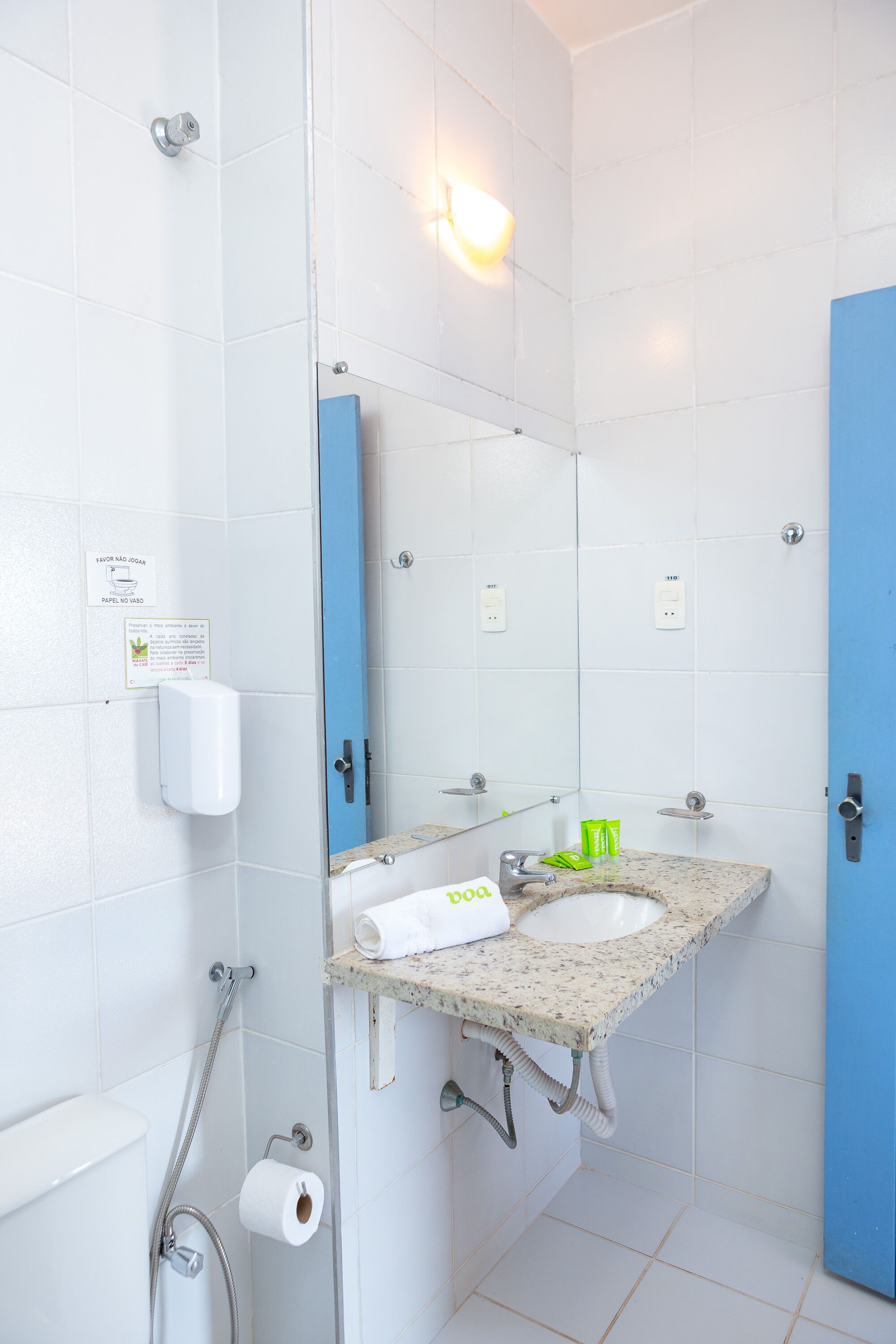 A bathroom with white tiles, a blue door, a sink with a mirror, a towel, and a toilet.