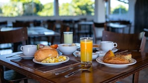 Et morgenbord med tallerkener med mad, et glas appelsinjuice og kopper.