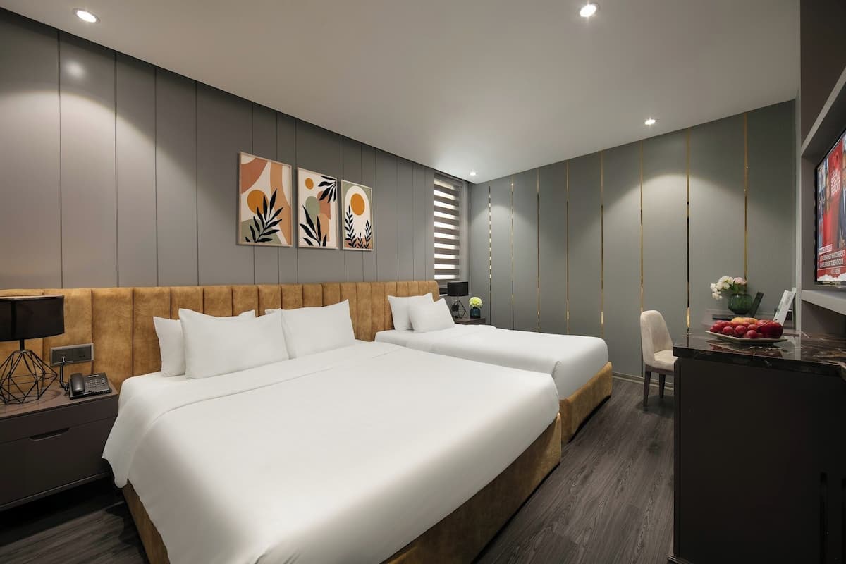A modern hotel room with two beds, a desk, and a chair.