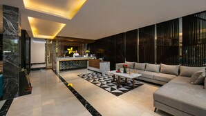 A modern hotel lobby with a reception desk, a sofa, and a patterned floor. - Ping Hanoi Hotel (Hanoi)