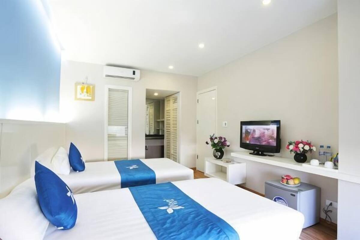 A hotel room with two beds, a television, a small table, and a desk with a computer.