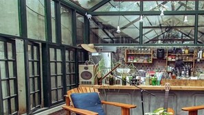 A cozy café with wooden furniture, a bar area, and large windows. - Ping Hanoi Hotel (Hanoi)