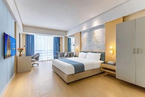 Une chambre d’hôtel moderne dotée d’un grand lit, d’un bureau, d’une chaise, d’une armoire et d’une grande fenêtre avec des rideaux.