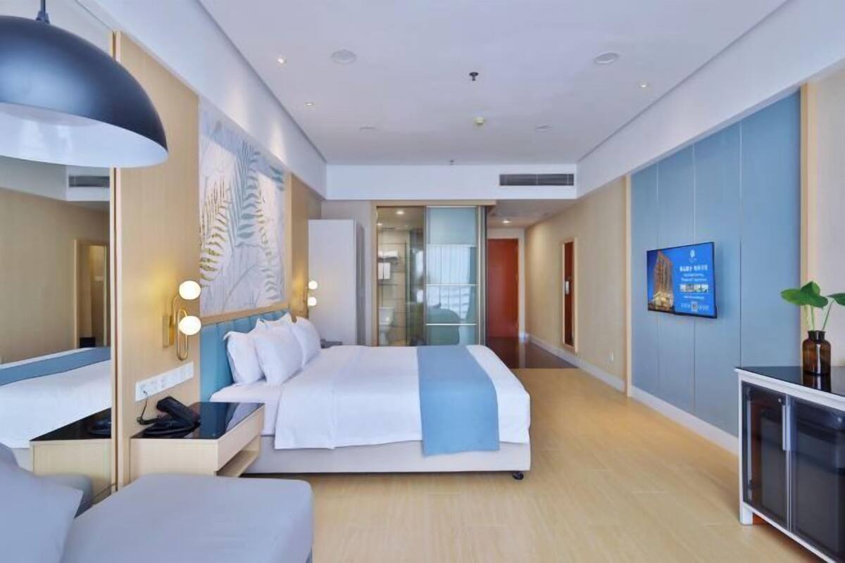 Una habitación de hotel moderna con una cama grande, una mesita de noche y un televisor en la pared.