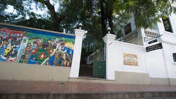 Un edificio con un mural en la pared, una verja verde y un letrero que dice "Pousada dos Quatro Cantos".