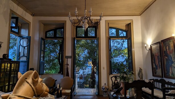 Una habitación con candelabro, ventanas amplias, una escalera y una estatua.