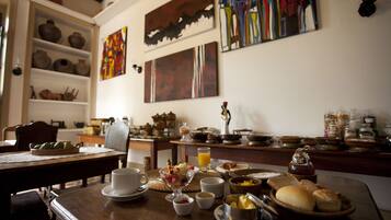 A breakfast table with various dishes, a coffee pot, and decorative items on shelves.
