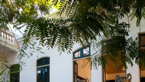 Una gran escalera con barandales ornamentados que conduce a un edificio blanco con contraventanas verdes.