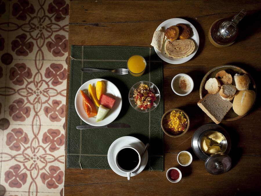 A breakfast table with plates of food, a cup of coffee, and a glass of orange juice.