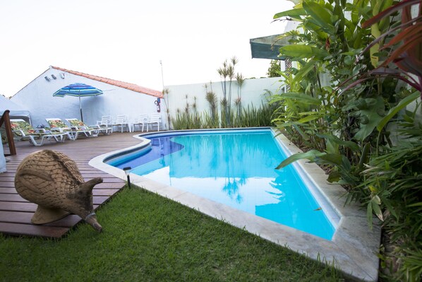 Una piscina al aire libre, sillones reclinables de piscina