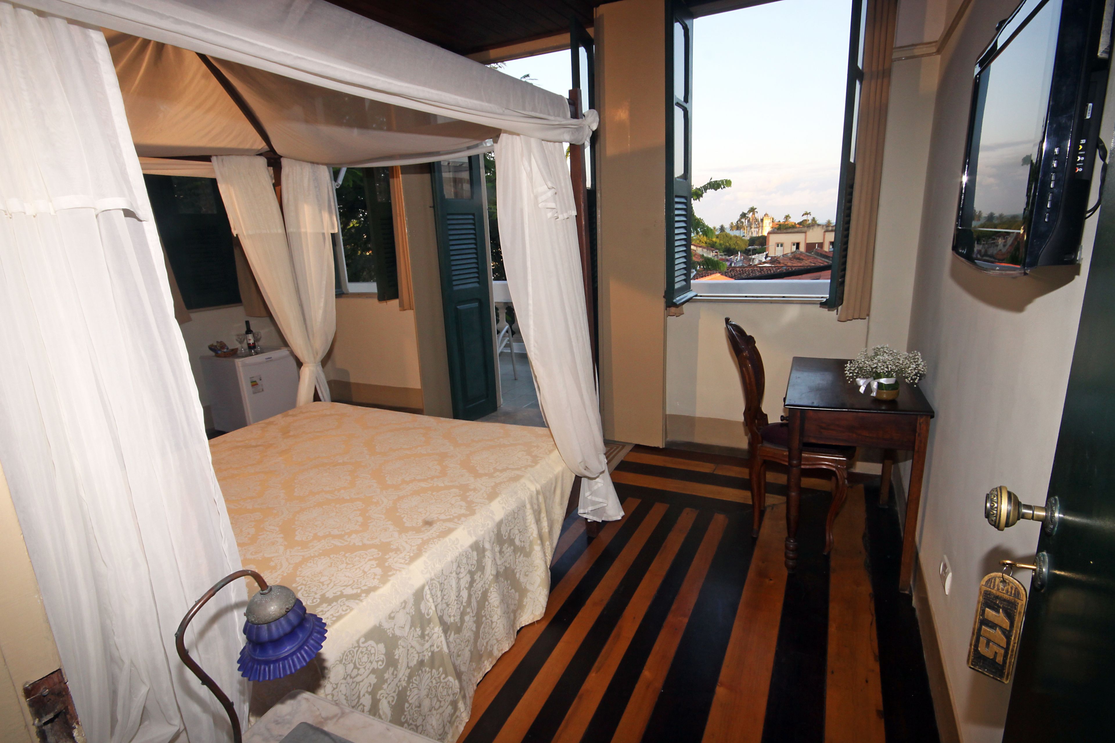 Una habitación con cama, escritorio, silla, ventana y puerta.