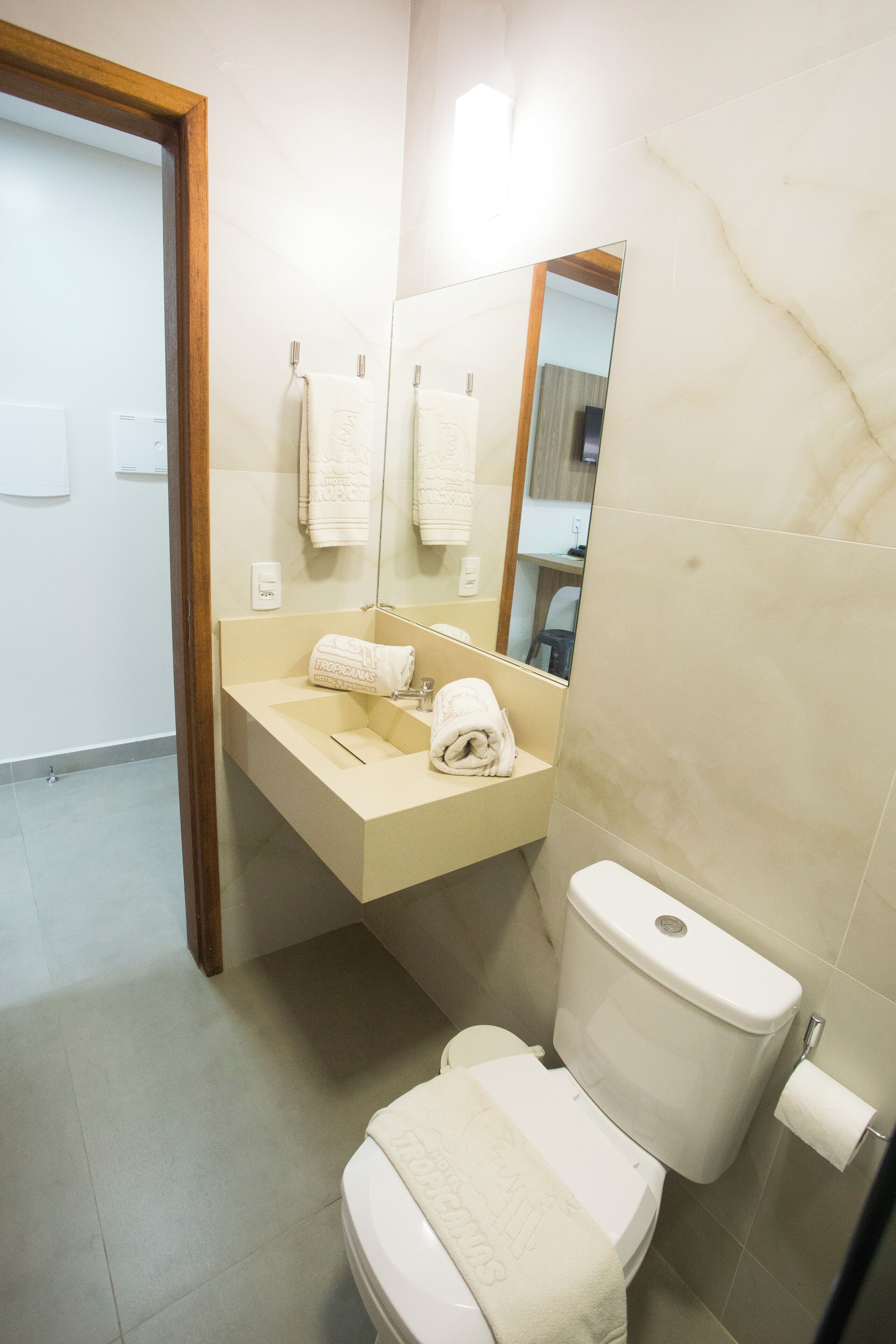 A bathroom with a toilet, sink, and mirror.