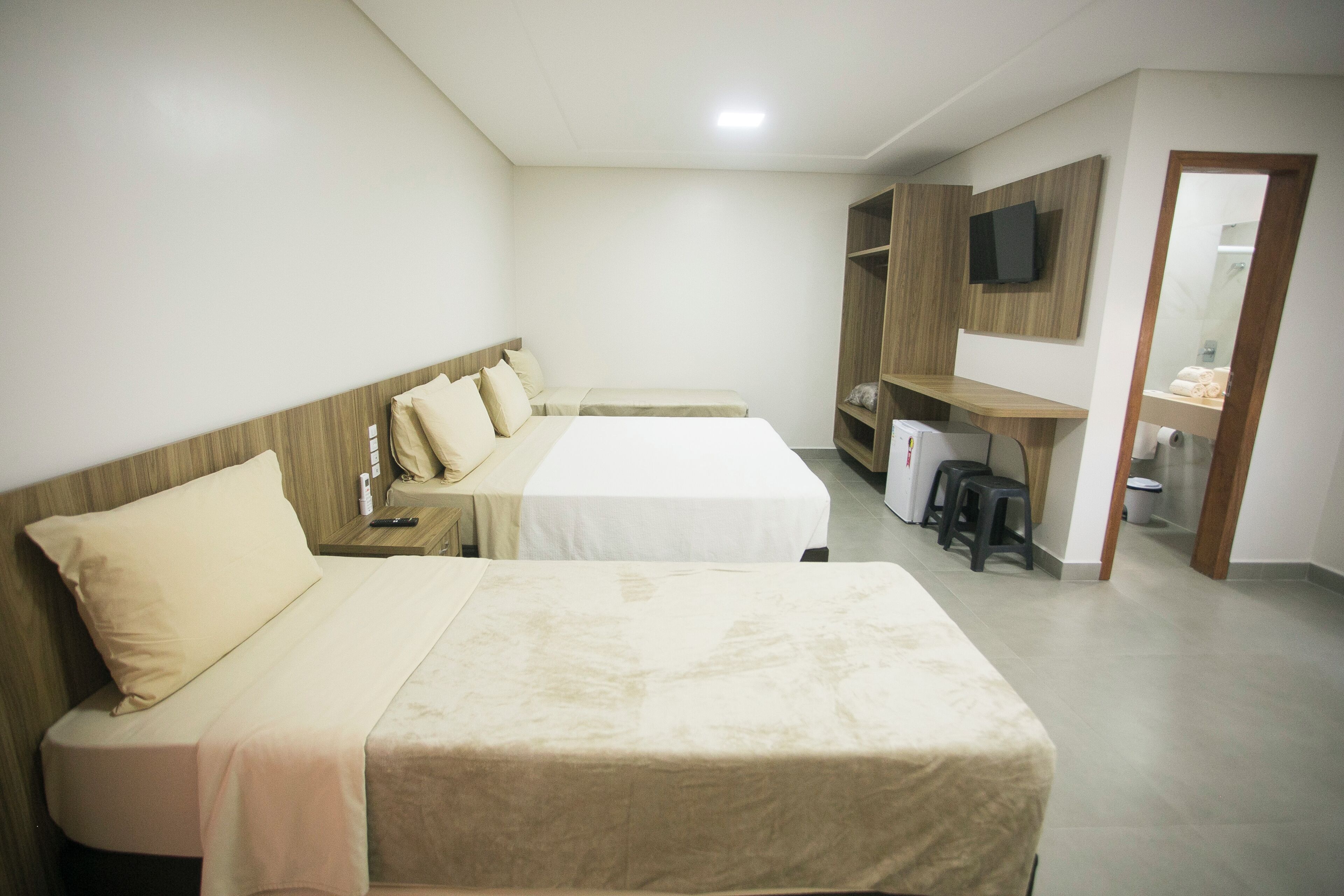 A hotel room with two beds, a TV, a desk, and a mirror.