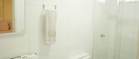 Un baño con lavamanos, inodoro y ducha blancos.