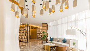 A modern lobby with a marble floor, a sofa with cushions, a coffee table, a floor lamp, and hanging pendant lights. - Atour Light Hotel Jinli Chengdu (Chengdu)