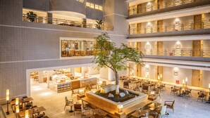 A multi-level hotel lobby with a central seating area, multiple dining tables, and a large tree. - Atour Light Hotel Jinli Chengdu (Chengdu)