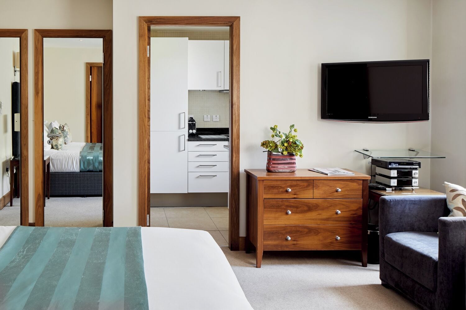 Un dormitorio con cama, cómoda de madera, televisor y una silla.