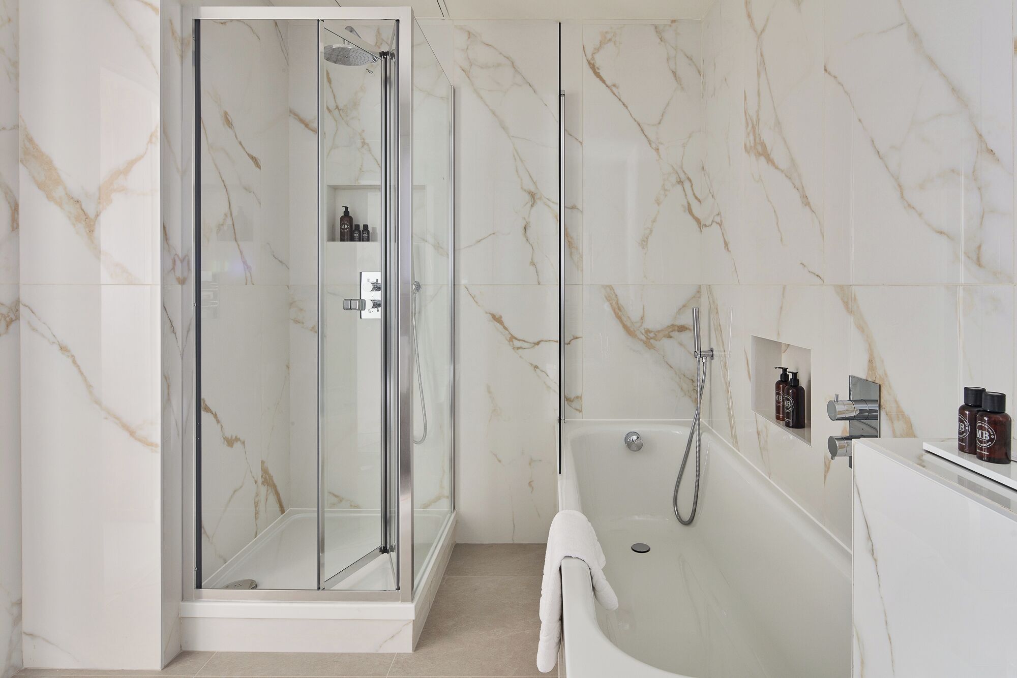 Un baño moderno con cabina de ducha de vidrio, bañera independiente y paredes de mármol.