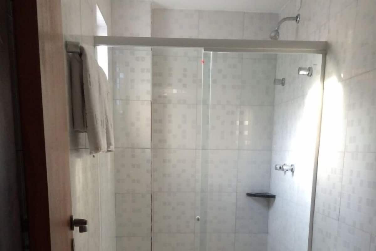 A modern bathroom with a glass-enclosed shower, a toilet, a sink, and a towel rack.