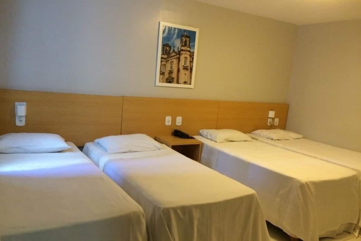 A hotel room with two single beds, a wooden headboard, a nightstand, and a framed picture on the wall.