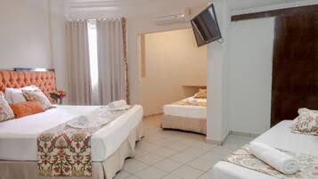 Quarto de hotel com duas camas, televisão na parede e banheiro visível através de uma porta aberta.