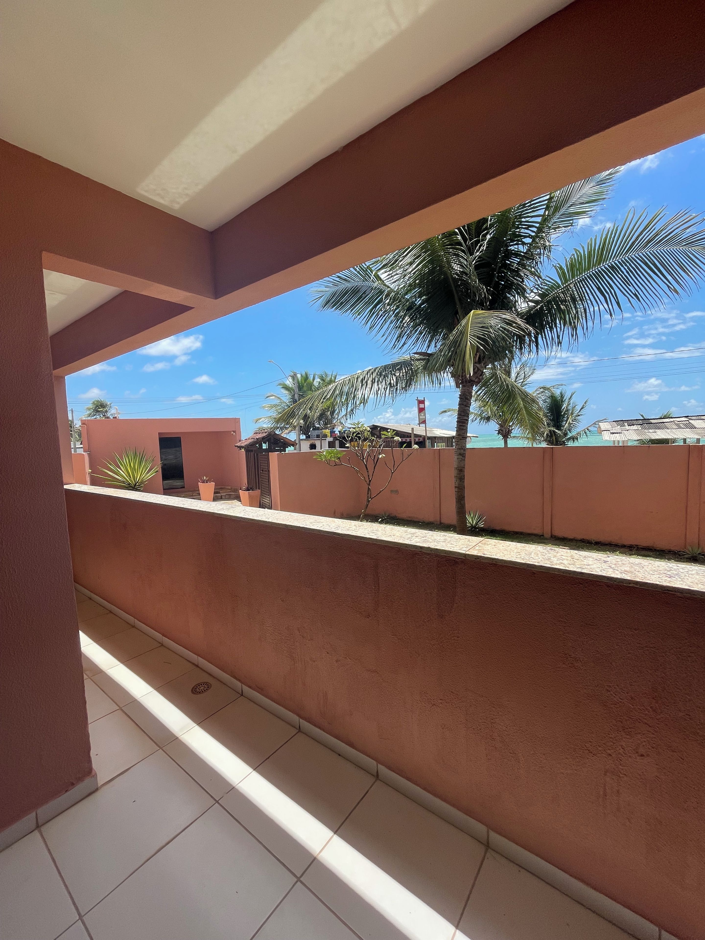 A balcony with a view of a palm tree and a clear sky.