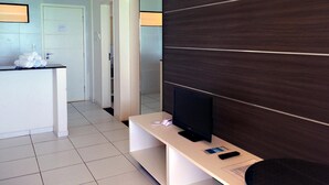 A hotel room with a TV on a stand, a mirror on the wall, and a small counter with towels. - Atlântico Hotel (Maceió)