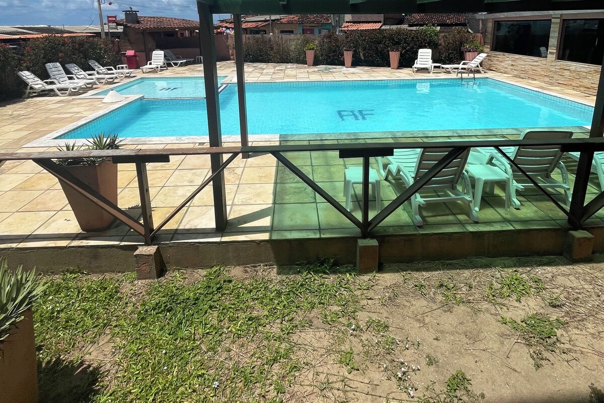 Une piscine avec des chaises longues et un espace abrité.
