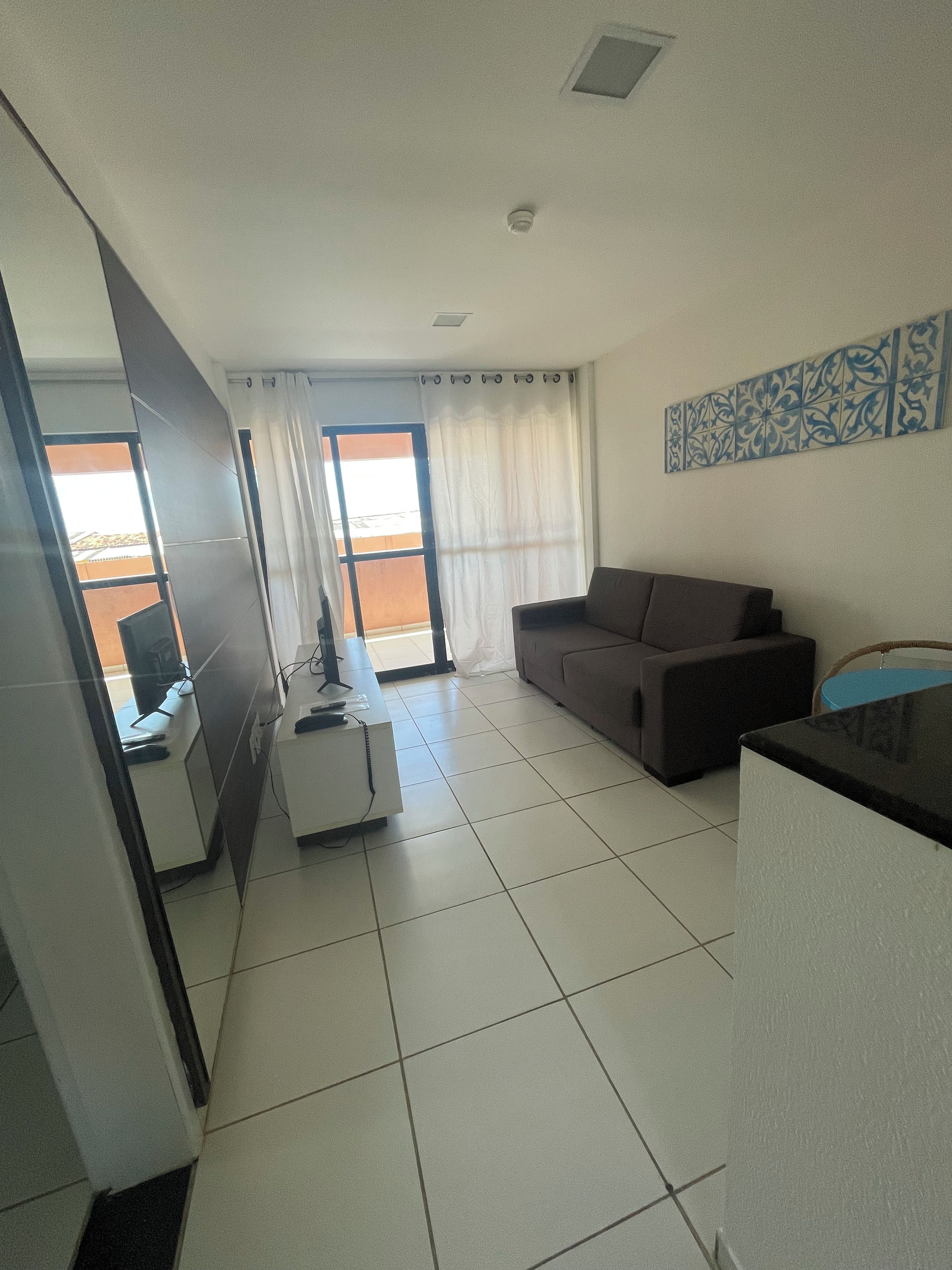 A modern living room with a sofa, a coffee table, and a dining area with a table and chairs.